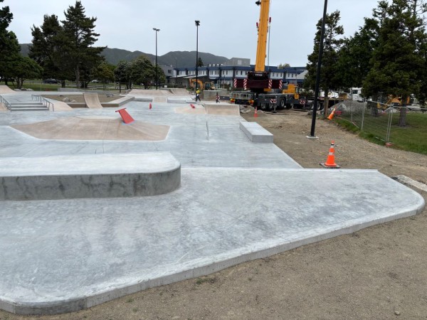 partially built concrete skatepark with wire fencing and digger in background 