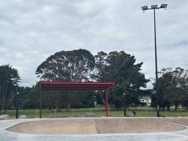 A red steel shelter protects the edge of a skatebowl from weather.